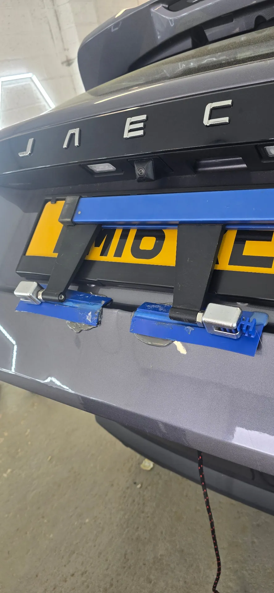 Glue-pull paintless dent repair tool in use on a Jaguar tailgate